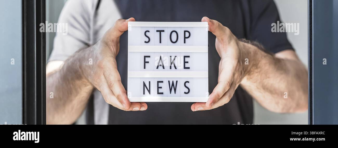 Fake News Infosemics during Covid-19 Pandemie Concept. Mann Hände halten Leuchtkasten mit Text Stoppen Fake News im Vordergrund. Die Leute wollen den Trut kennen Stockfoto