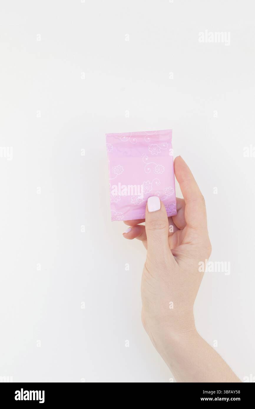 Frau hand mit Pastellfarben Maniküre polnischen Holding Rosa täglich Binde auf weißem Hintergrund mit Kopie Raum isoliert. Vorlage für weibliche Schönheit b Stockfoto