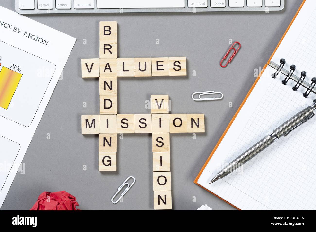 Markenwertkonzept mit Wörtern aus Cubes. Stillleben des Büroarbeitsplatzes mit Kreuzworträtsel. Flache graue Oberfläche mit Notebook und Infografiken. Strate Stockfoto