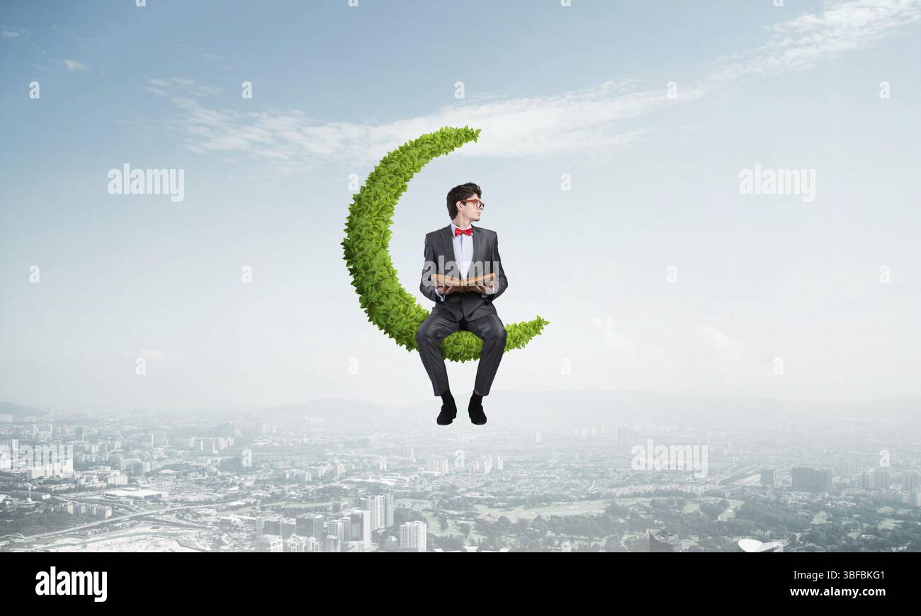 Junger Student sitzt auf dem Symbol des Mondes aus der Pflanze Stockfoto