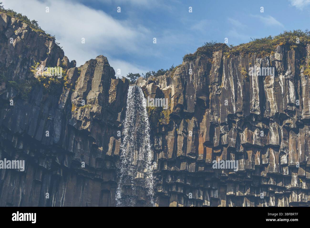 Wasserfall Svartifoss in Island unter einem blauen Himmel mit Wolken Stockfoto