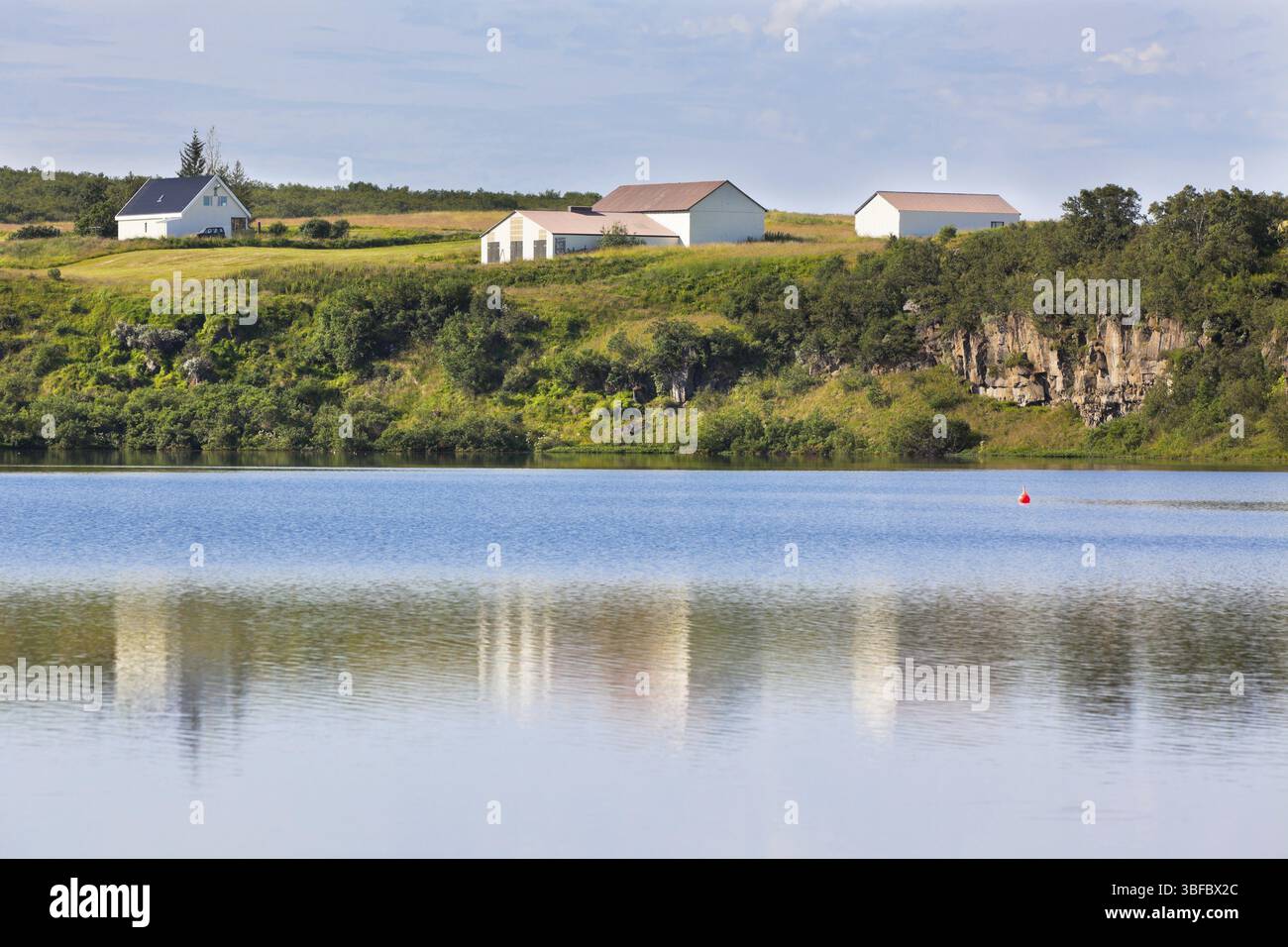 Island-Landschaft mit See und Bauernhaus am sonnigen Schönwetter Stockfoto