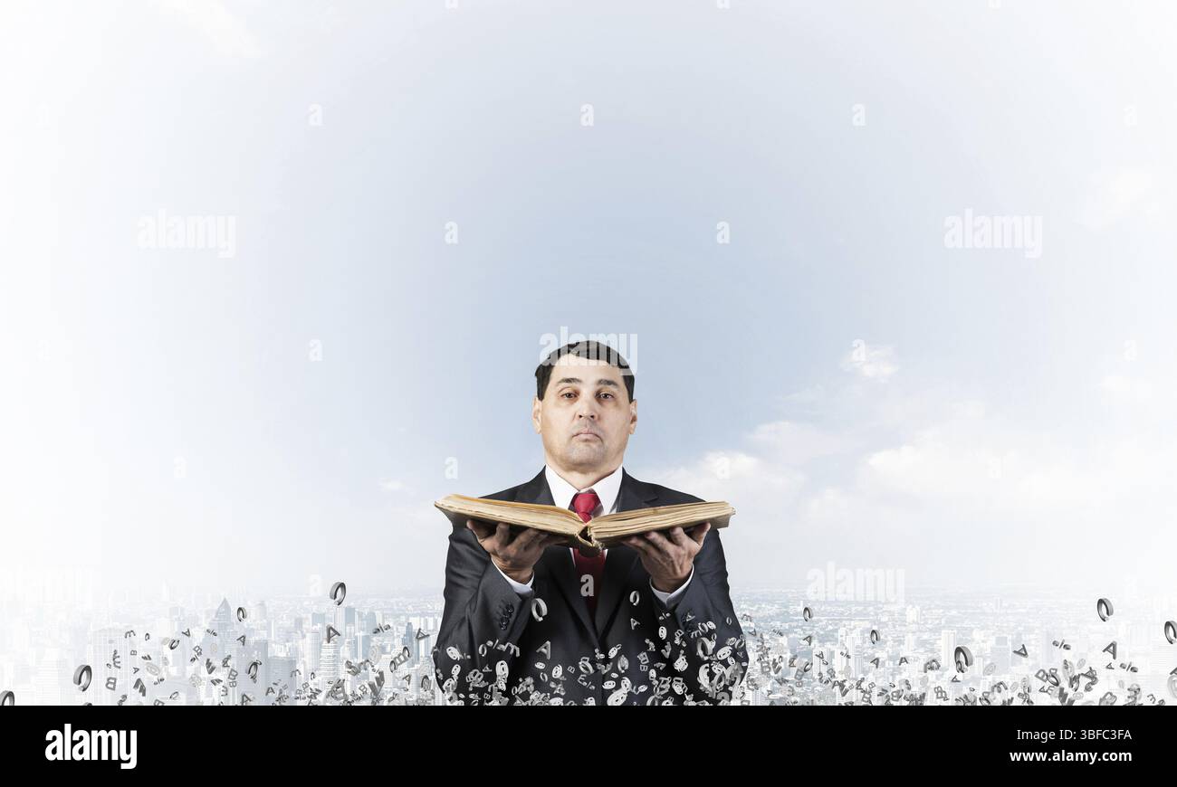 Senior Geschäftsmann Holding alte Buch öffnen. Mann in Anzug und Krawatte stehen auf stadtbild Hintergrund mit fliegenden rund um verschiedene Buchstaben. Manager ho Stockfoto