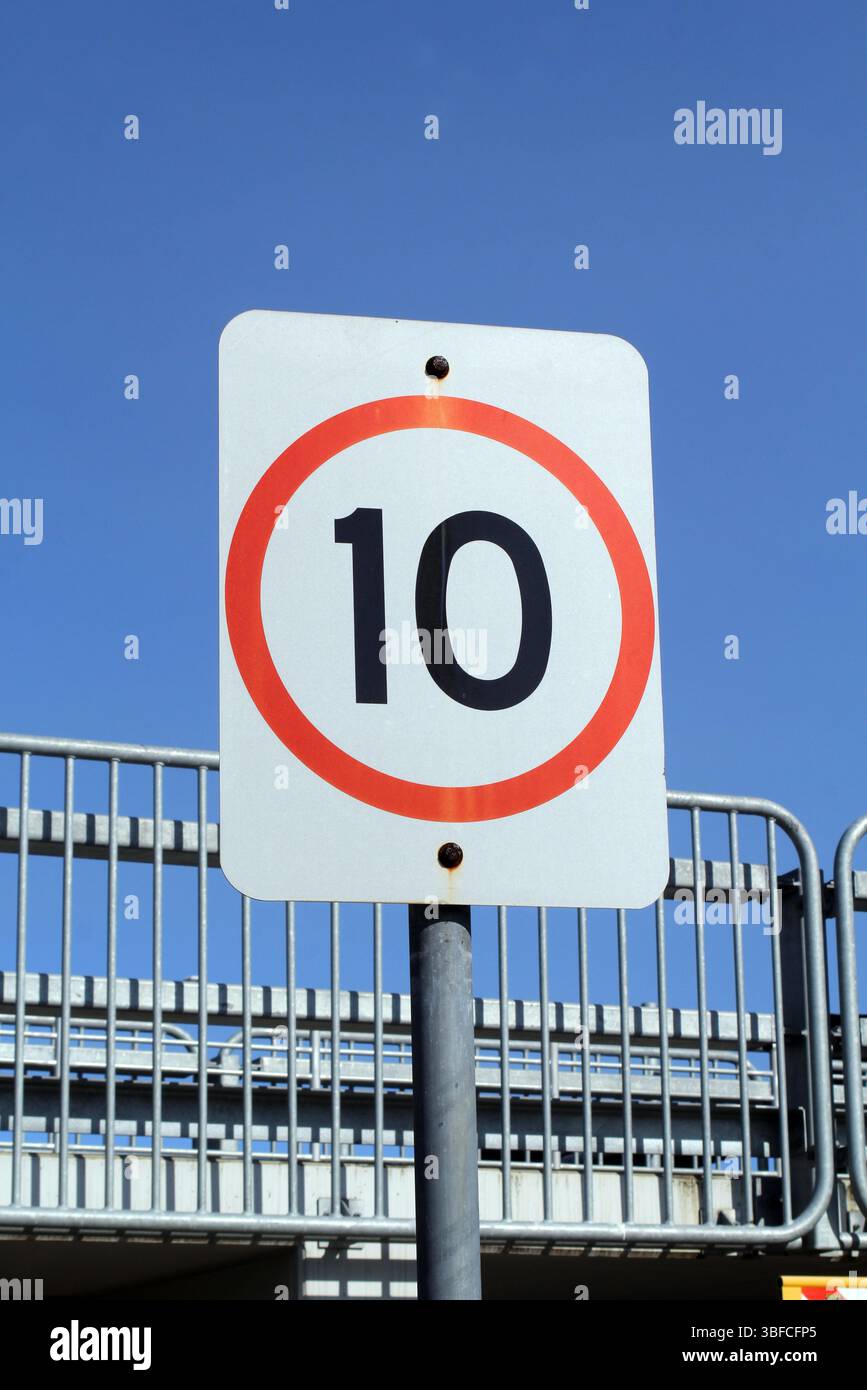 10 km/h Geschwindigkeitsbegrenzung Verkehrsschild auf einem Mast mit einem Metallzaun und dem Himmel im Hintergrund Stockfoto