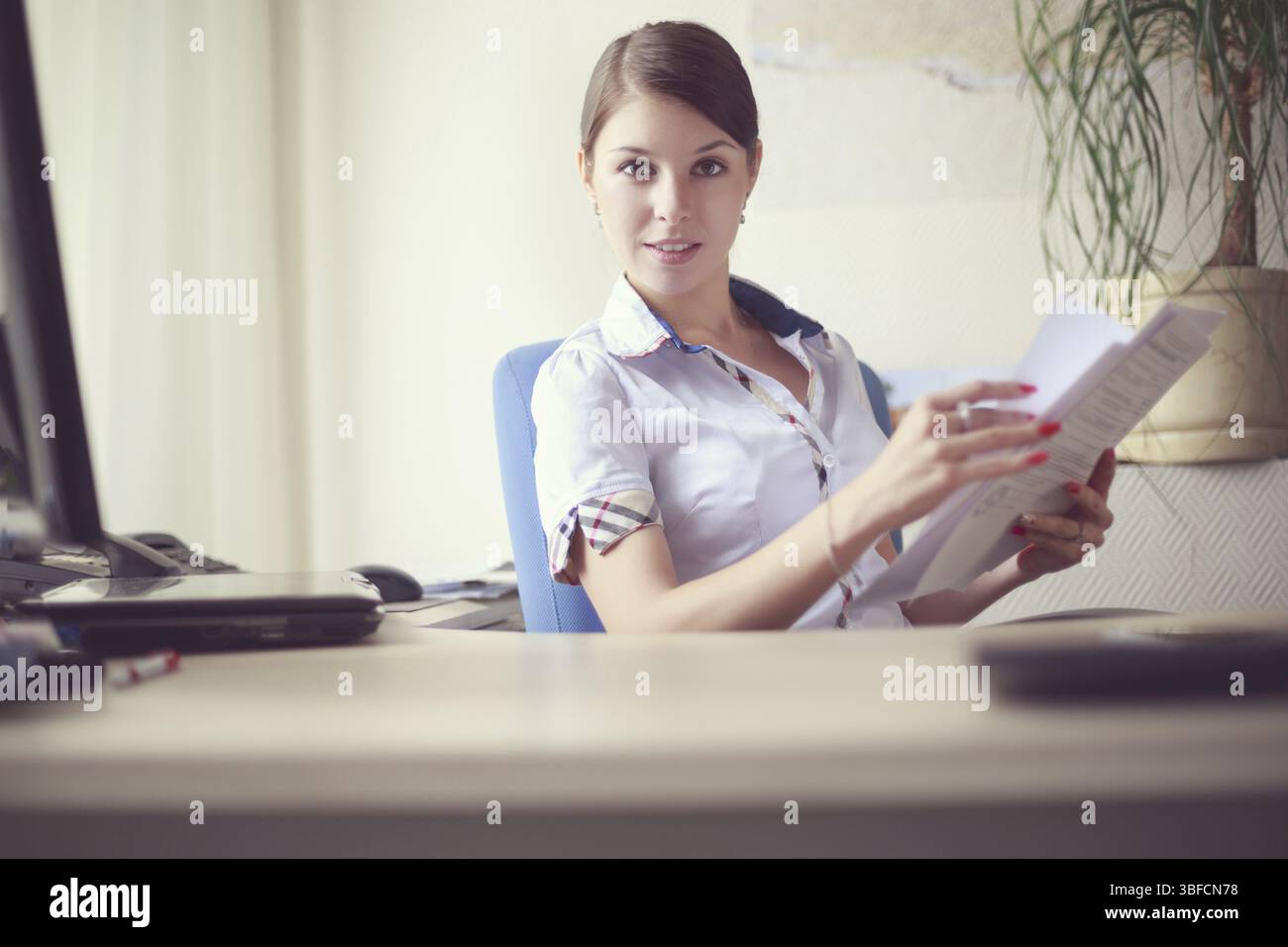 Porträt einer jungen kaukasischen Geschäftsfrau in weißem Hemd mit kurzen Ärmeln im Büro Stockfoto