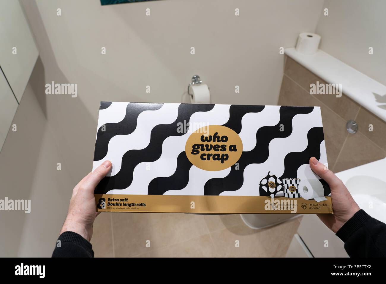 Mann mit einer Schachtel Bambus-Toilettenpapier in einem Badezimmer von der australischen Firma und Marke, die Einen Mist gibt, B Corp und FSC zertifiziert, Großbritannien Stockfoto