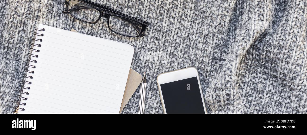 Kreative Herbst flach overhead Draufsicht stilvolle Home Arbeitsbereich mit Smartphone notebook gemütlichen grau gestrickt plaid Lange breite Hintergrund Kopie Raum. Fa Stockfoto