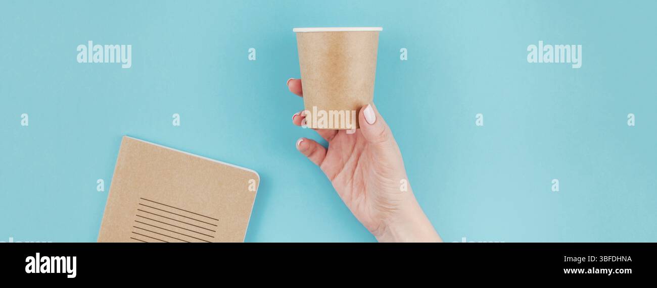 Lange breite Banner der Frau Hand Handwerk Papier Kaffeetasse und Notizbuch Tagebuch mit Kopie Speicherplatz auf Türkisfarbenem Hintergrund in minimalistischem Stil. Vorlage Stockfoto
