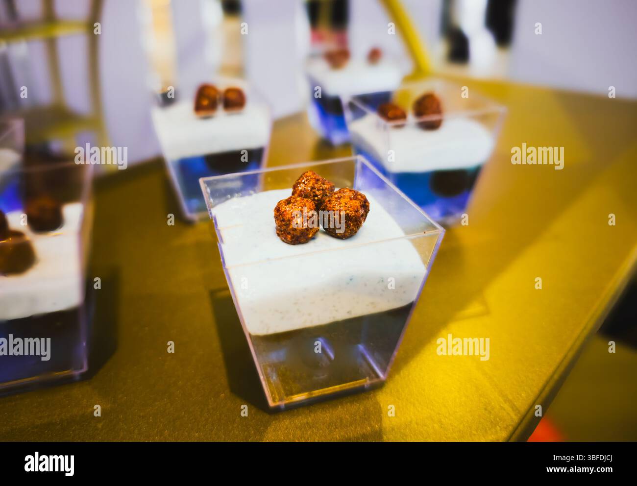 Modernes Dessert in mehreren Schichten in Plastikbecher mit knusprigem Schokoladenbelag Stockfoto
