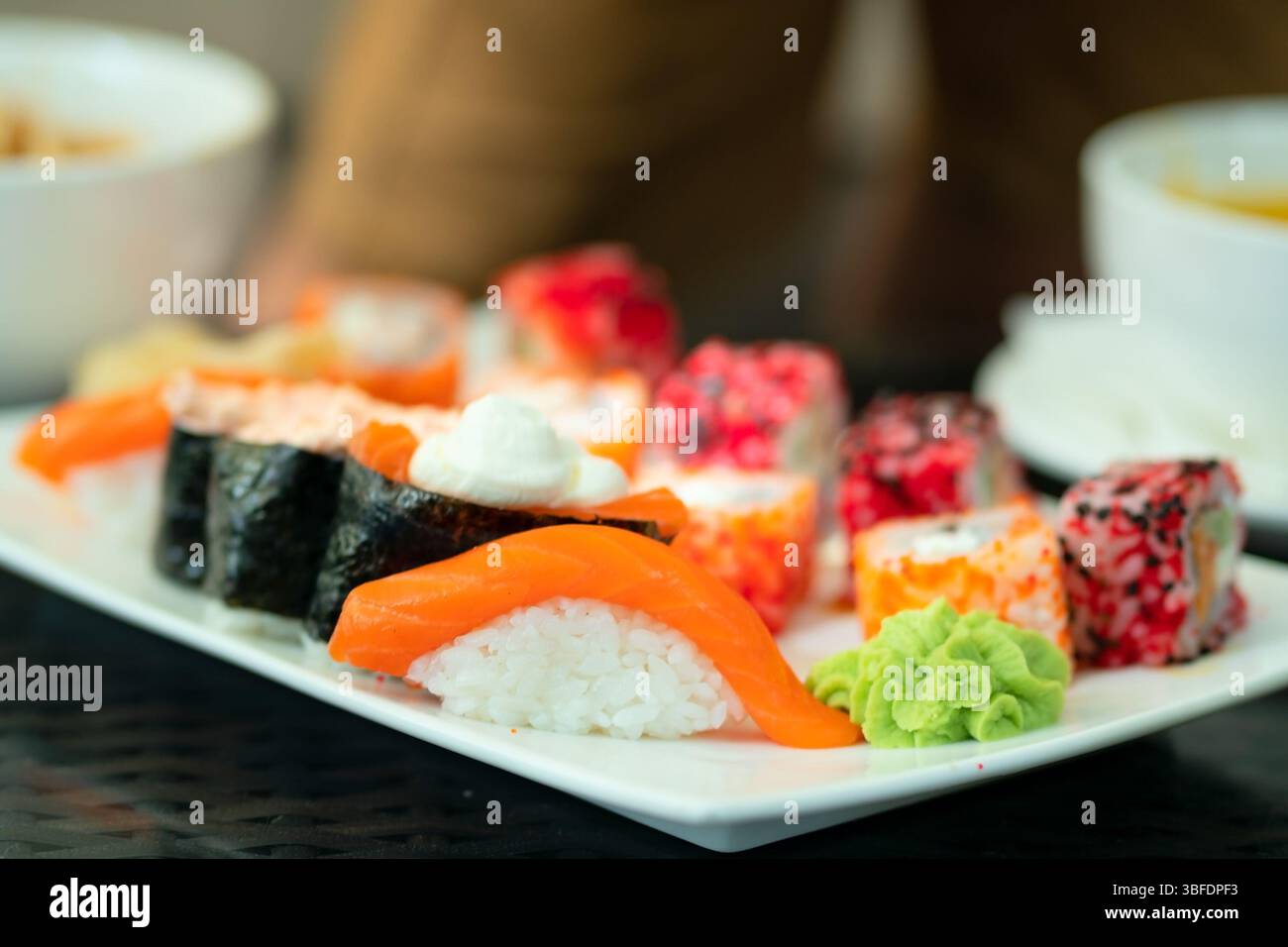 Bunte Auswahl an authentischen Sushi-Brötchen und Nigiri mit frischen Meeresfrüchten. Schöne Präsentation von nahrhaftem japanischem Fast Food. Stockfoto