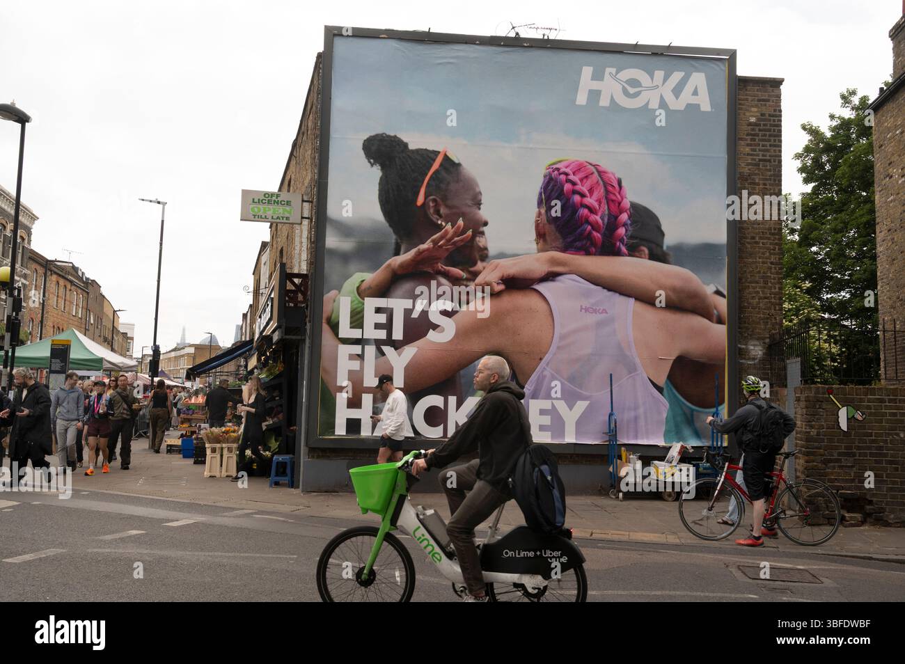 East London, Hackney, Broadway Market. Werbespot mit Werbespot für Hoka Sportswear Company mit einem Foto von drei jungen Frauen Stockfoto