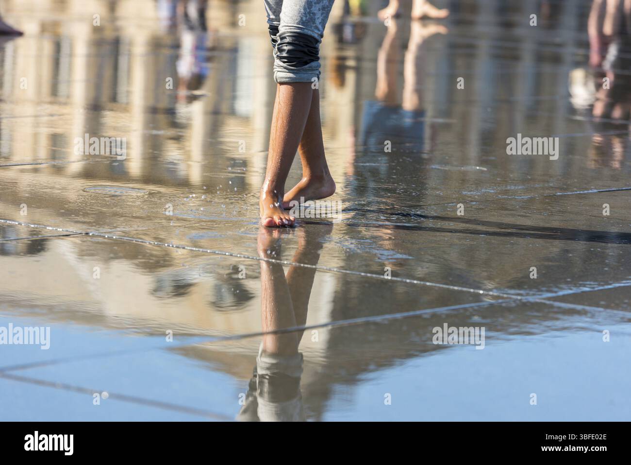 Leute, die sich in einem Spiegelbrunnen vor dem Place de la Bourse in Bordeaux, Frankreich, Europa amüsieren Stockfoto