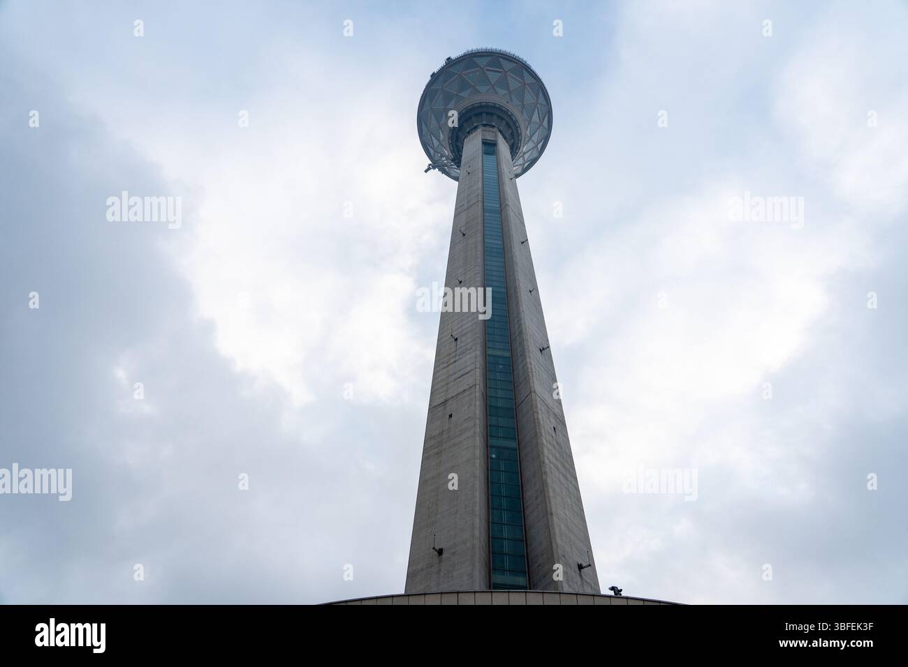 Teheran, Iran - 12. November 2023: Dramatische Perspektive des Milad Tower, der in den bewölkten Himmel steigt Stockfoto