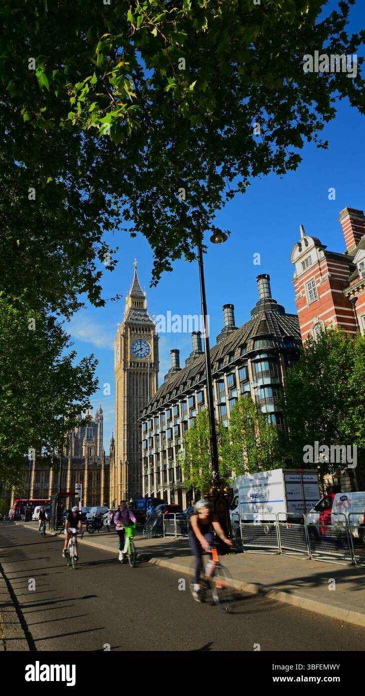 Vormittag am Victoria Embankment mit Radfahrern, Verkehr und Big Ben im Hintergrund und grünen Bäumen unter blauem Himmel, Westminster, London. Stockfoto