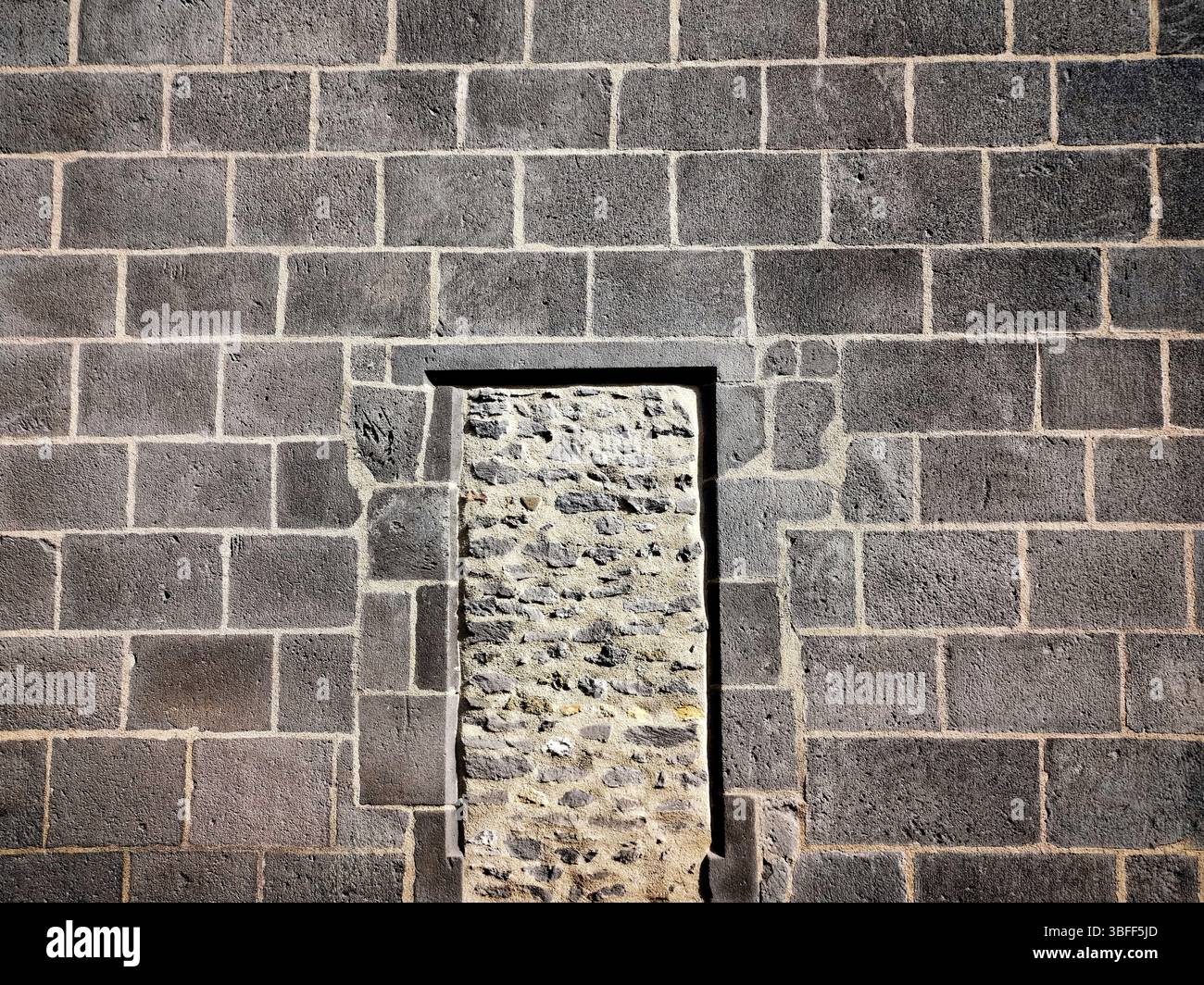 Diese Struktur verfügt über eine Steinmauer aus rauem Mauerwerk mit einem eigenständigen Eingang, der in rechteckiger Form umrahmt ist - Smartphone-aufgenommenes Stockfoto