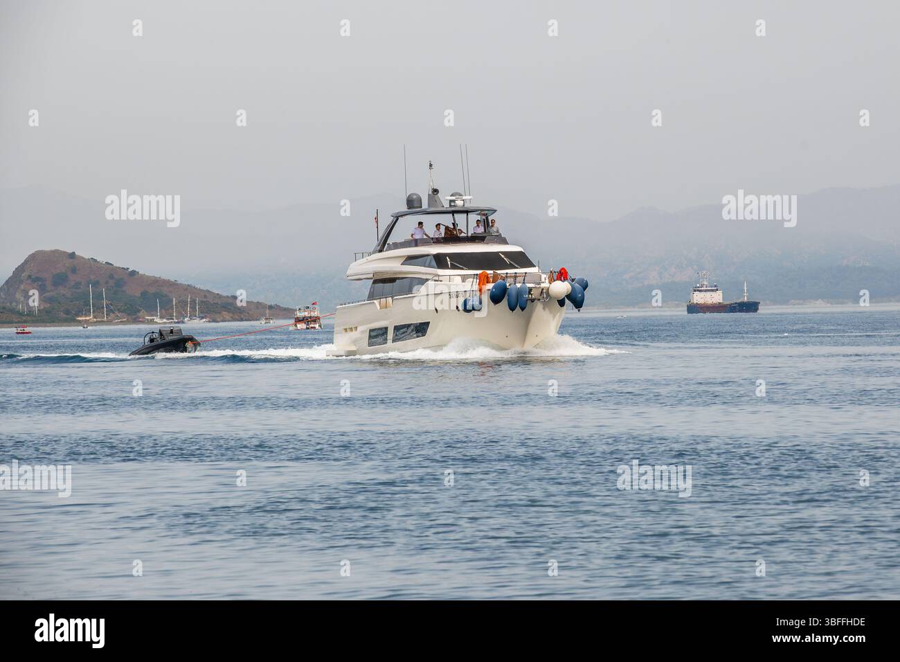 Moderne Luxus-Motoryacht gleitet durch das Meer, mit einem kleinen aufblasbaren Boot hinter sich. Die Szene zeigt High-End-Seefahrten. Stockfoto