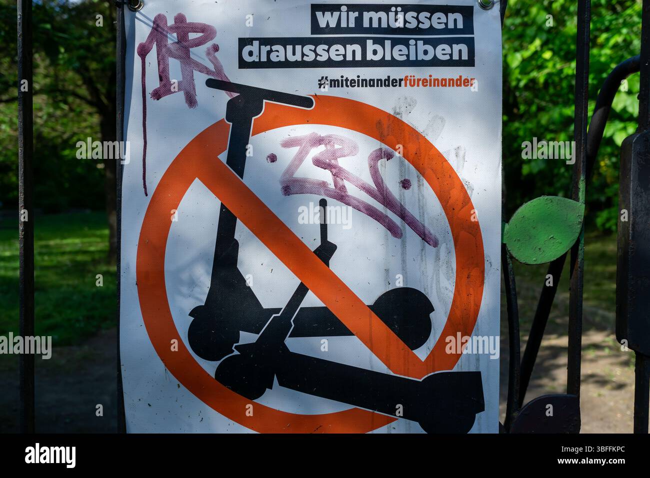 Verbotsschild gegen E-Scooter am Eingang zum Park Weißer See in Berlin, mit Graffiti und Kampagnenbotschaft. Stockfoto