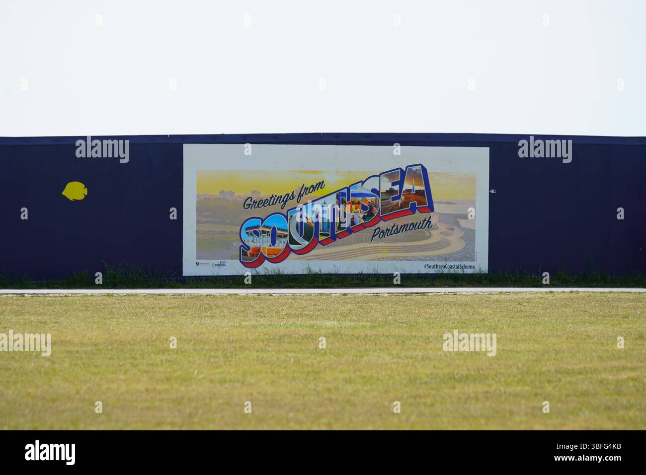 Grußworte aus Southsea Poster auf blauem Außenzaun mit Gras im Vordergrund. Portsmouth, Großbritannien Stockfoto