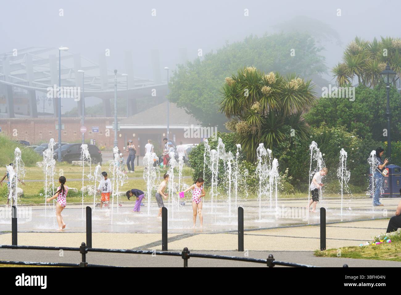 Kinder, die an einem nebeligen Sommertag im Fountain Splash Pad spielen. Portsmouth, Großbritannien Stockfoto