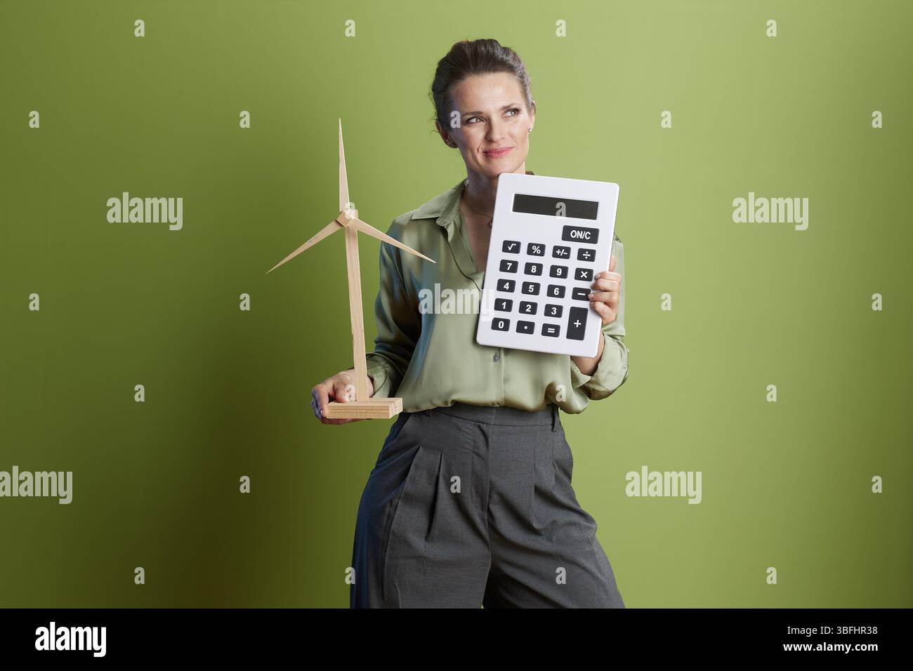 Eine Frau besitzt einen Rechner und eine Windkraftanlage, die nachhaltige Finanzierung, Investitionen in grüne Energie und zukunftsorientiertes Denken fördert. Stockfoto