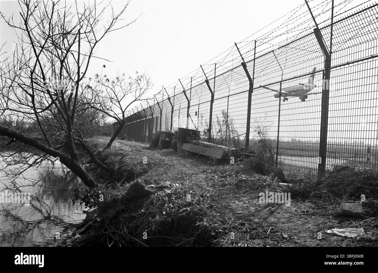 Anfang der 2010er Jahre China Airport Perimeter Fence mit Landungsflugzeug und Rural Canal Stockfoto
