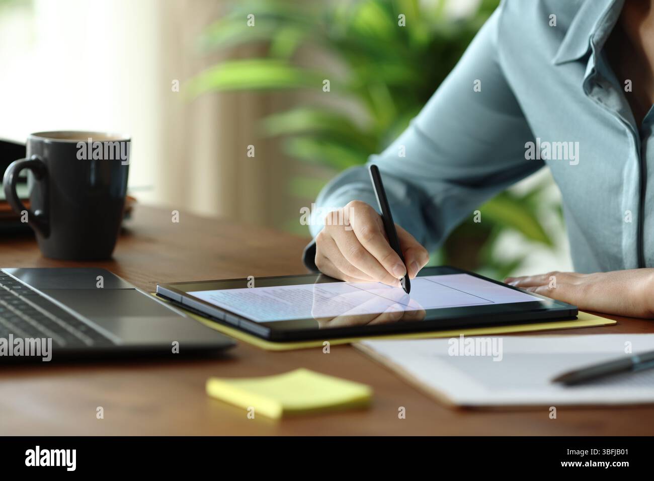 Nahaufnahme einer Frau Handschrift auf Tablette auf Holztisch Stockfoto