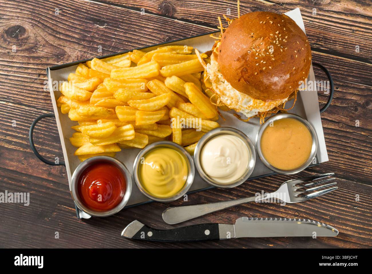 Eierburger mit knusprigen Kartoffeln serviert mit Pommes und Saucen Stockfoto