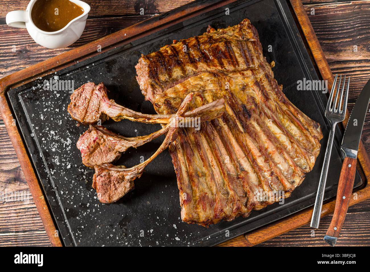 Lammregale gegrillt mit Kräutern und Soße auf einem Steinbrett Stockfoto