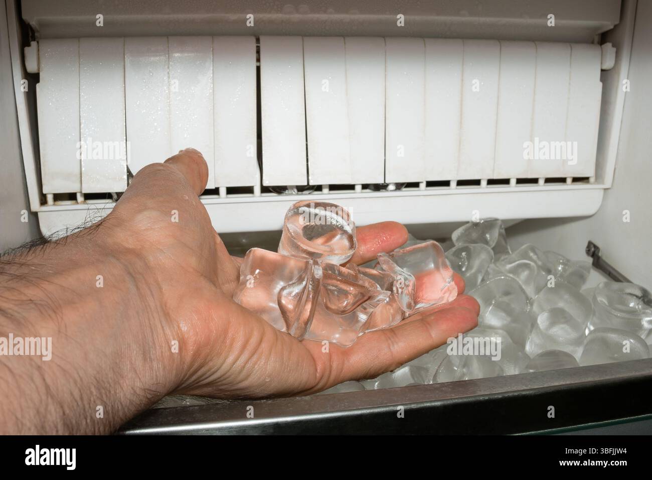 Eiswürfel auf der Palme eines Mannes in einer Eismaschine. Stockfoto