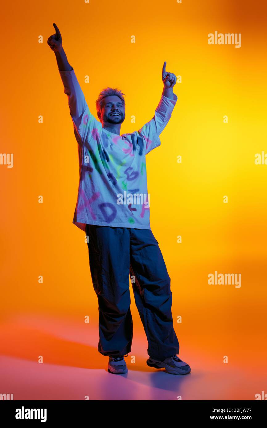 Ein hübscher junger Mann zeigt seine Tanzbewegungen und strahlt Energie vor einem hellen Hintergrund aus. Stockfoto