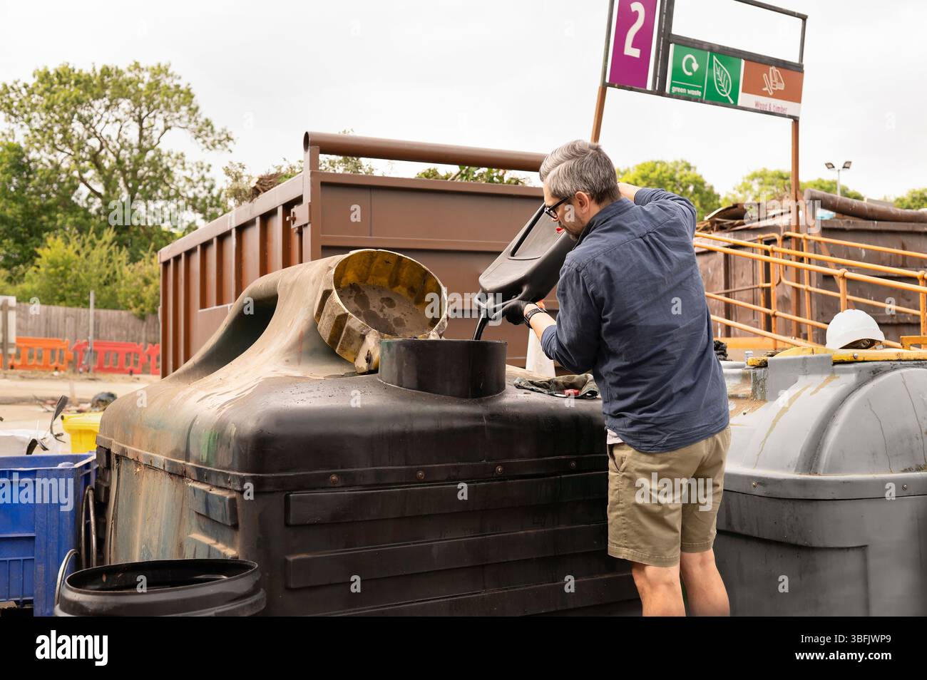 Man gießt Motoröl in den Behälter im Recyclingzentrum. Stockfoto