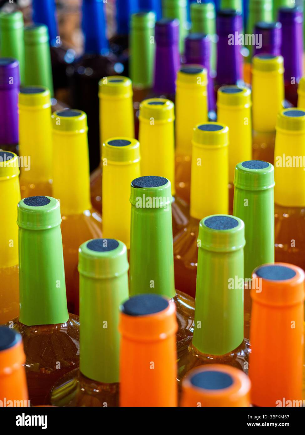 Farbenfrohe Flaschenoberteile mit abstraktem Design in Grün, Orange, Gelb und Lila. Stockfoto