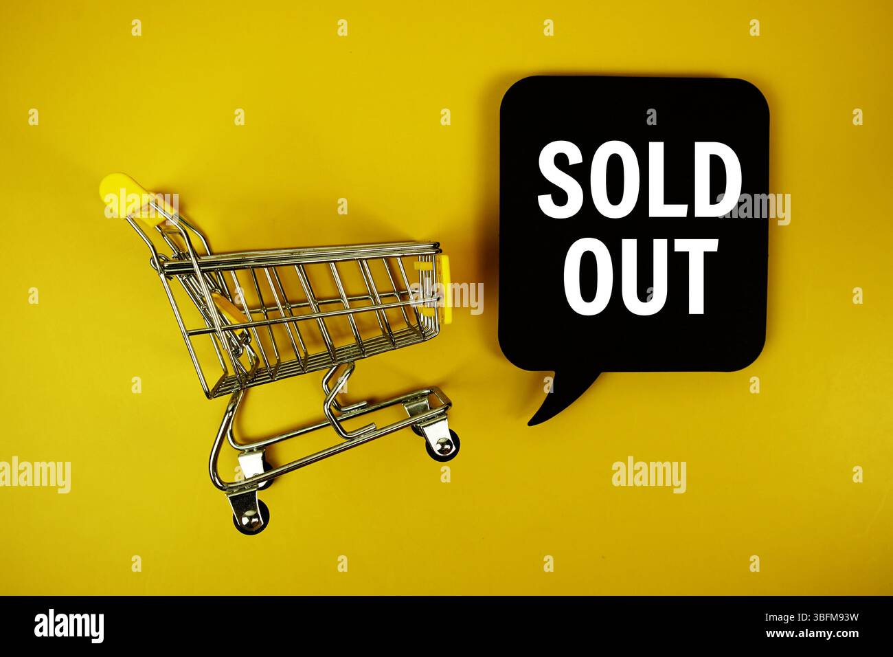 Ausverkaufter Text auf Sprechblase mit Mini-Einkaufswagen von oben auf gelbem Hintergrund Stockfoto