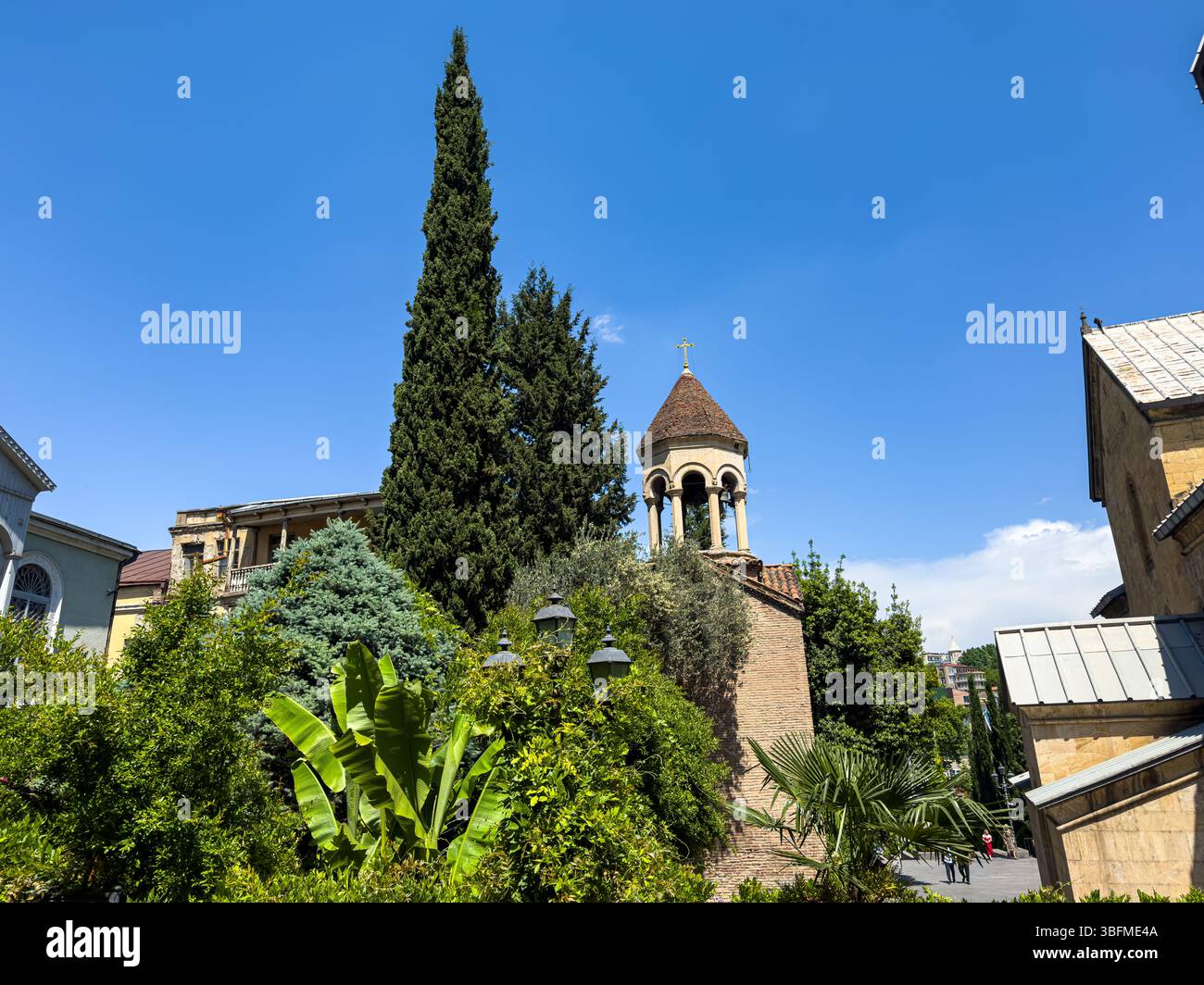 Historischer Kirchturm umgeben von Grün in Tiflis, Georgien. Klarer blauer Himmel, Sommertag, keine Leute aus der Nähe. Stockfoto