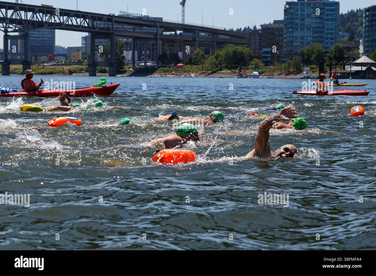 The Big Float, Portland, Oregon – 15. Juli 2017: Schwimmer überqueren den Willamette River, unterstützt von Kajakfahrern, für eine lustige Sommerveranstaltung. Stockfoto