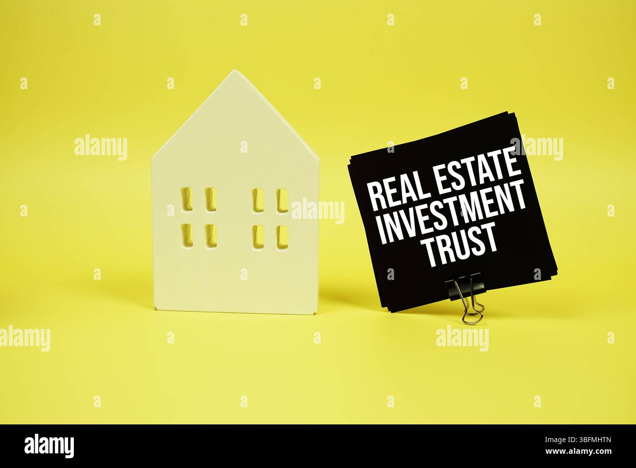 Real Estate Investment Trust Text mit Hausmodell auf gelbem Hintergrund Stockfoto