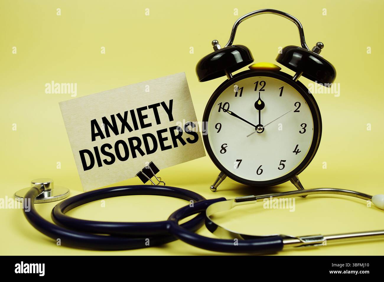 Angststörungen Textnachricht auf Papierkarte mit Stethoskop und Wecker auf gelbem Hintergrund Stockfoto
