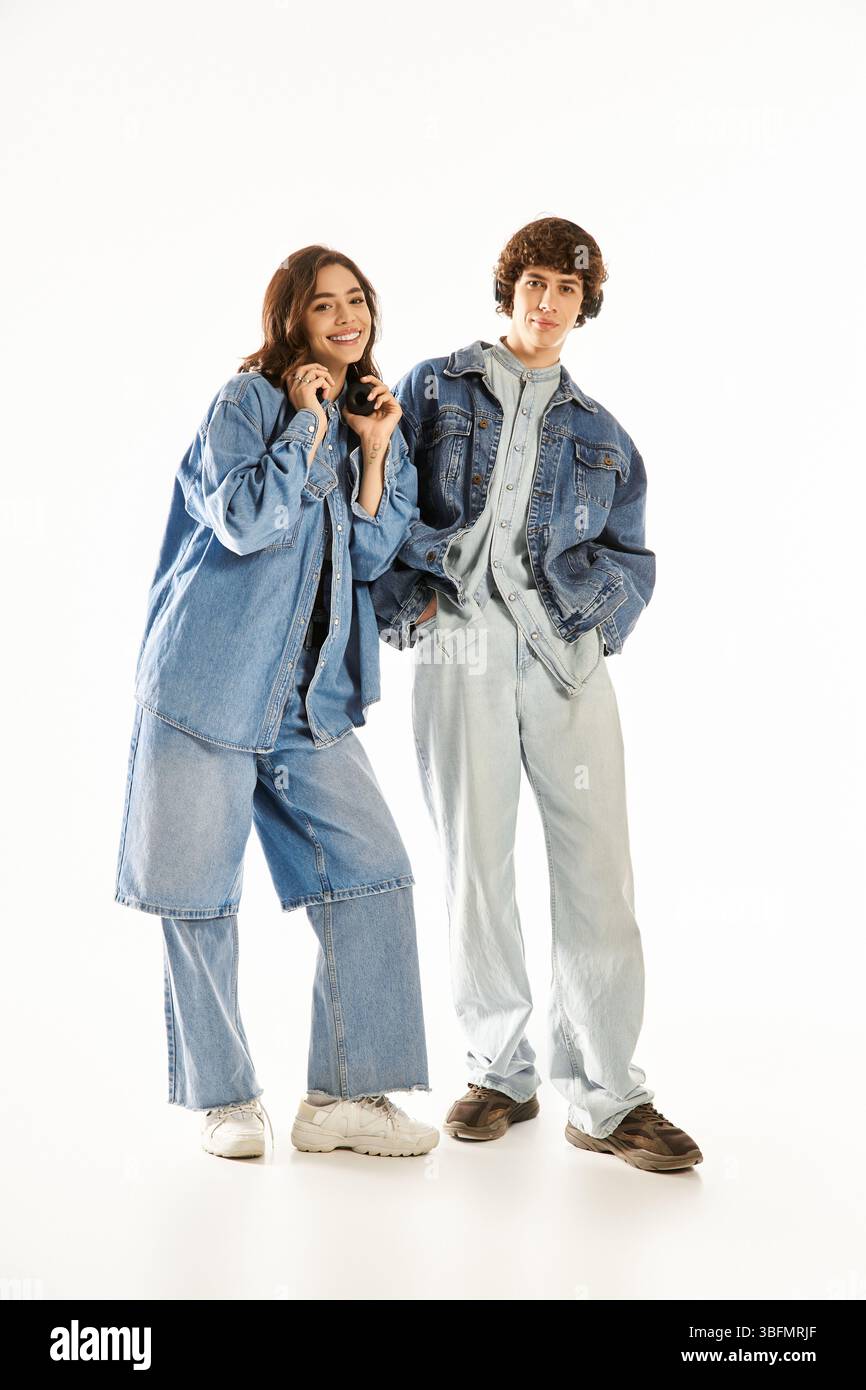 Liebevolles Paar in stilvollem Denim, lächelnd und in einem hellen Raum zusammen mit anderen genießt. Stockfoto