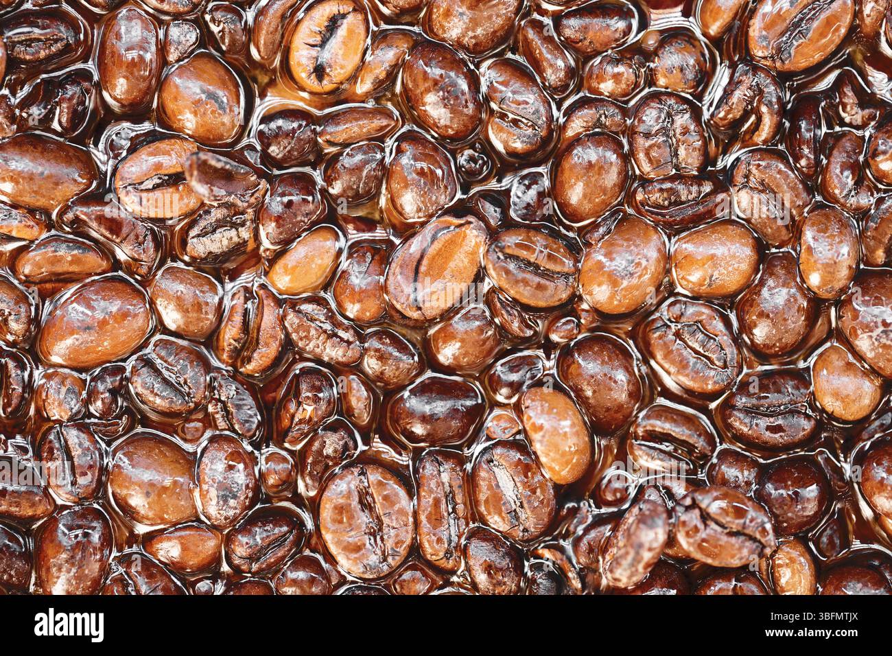 Kaffeebohnen in Epoxidharz. Künstlerischer Texturhintergrund. Dunkelbraun gerösteter Kaffee. Kreative dekorative Oberfläche. Glänzende Bohnen, haltbar gemacht. Stockfoto