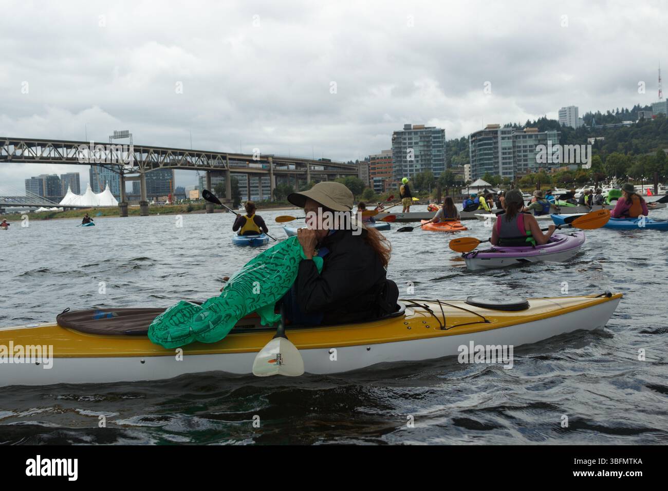 The Big Float, Portland, Oregon – 10. Juli 2016: Eine Frau bläst einen Spielzeug-Alligator auf, während sie im Willamette River Kajak fährt. Stockfoto