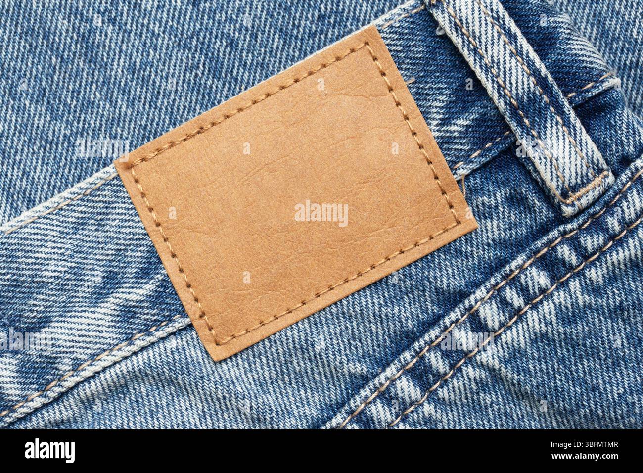 Jeanstasche mit Lederetikett. Makro mit modischen Details. Legere Kleidung Textur. Modernes Outfit. Nahaufnahme der Bekleidungsherstellung. Stockfoto