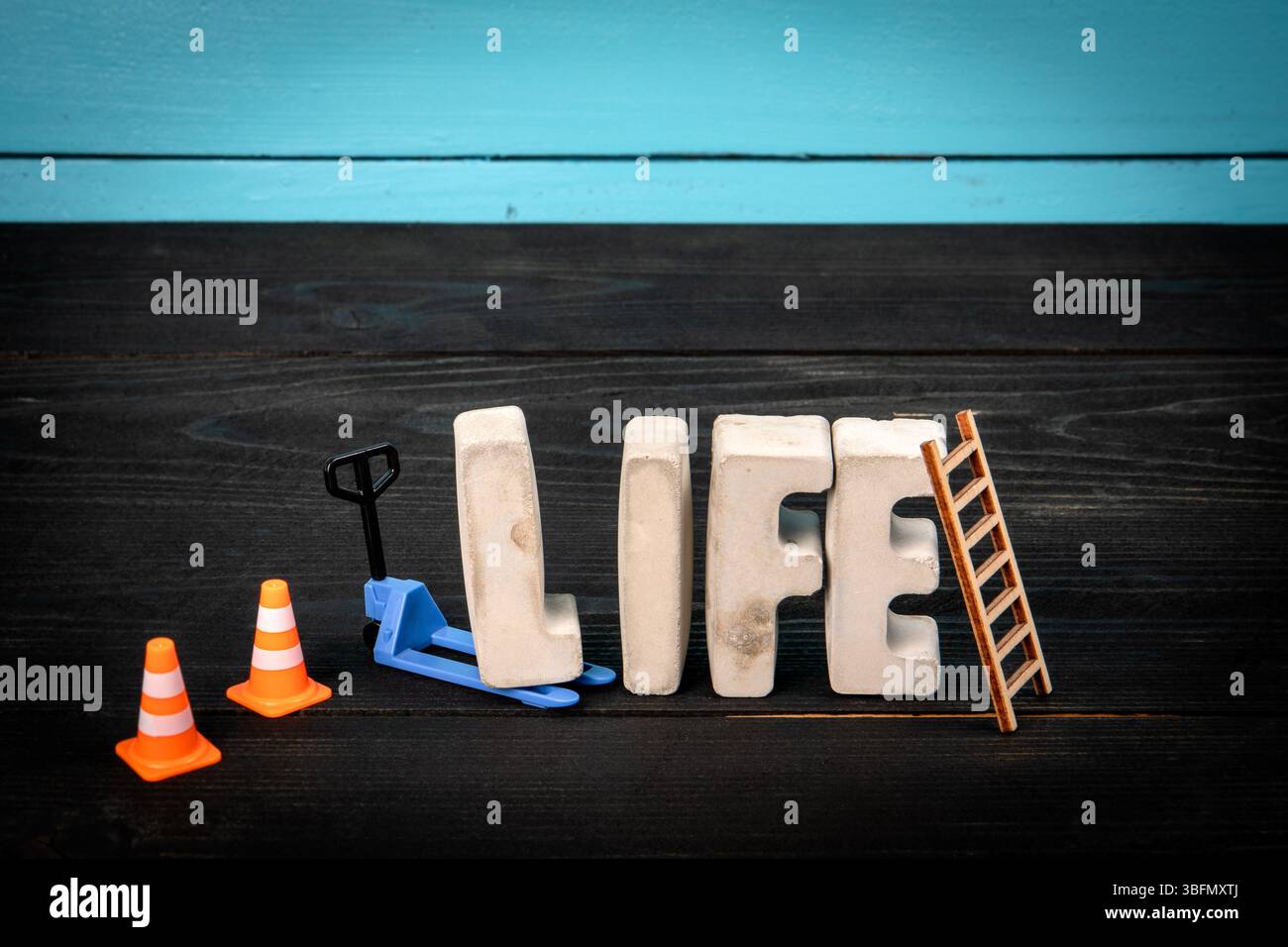 LIFE-Konzept. Betonbuchstaben auf blauem und schwarzem hölzernem Hintergrund. Stockfoto