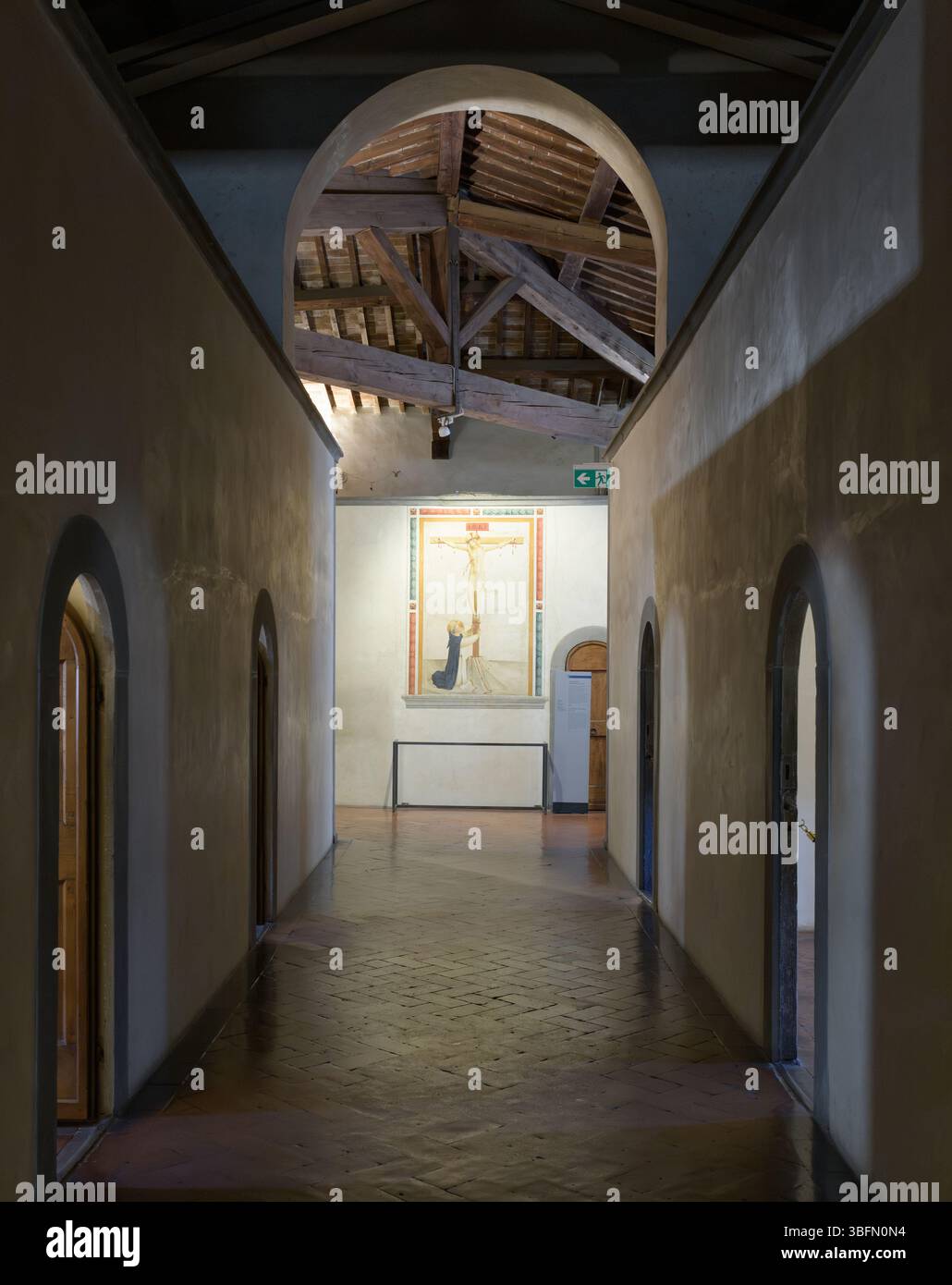 Blick auf den gewölbten Korridor im San Marco Kloster, Florenz, mit Fra Angelico Fresko des Heiligen Dominikus am Kruzifix. Stockfoto Blick auf den gewölbten Korridor im San Marco Kloster, Florenz, mit Fra Angelico Fresko des Heiligen Dominikus am Kruzifix. Stockfoto