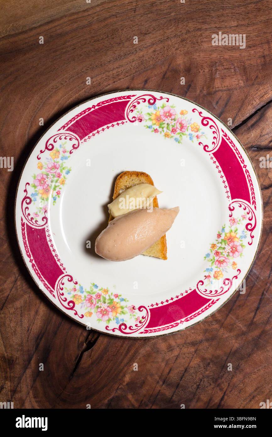 Toast mit Pastete auf einem Blumenteller. Ein Snack wird auf einem Holztisch serviert. Stockfoto
