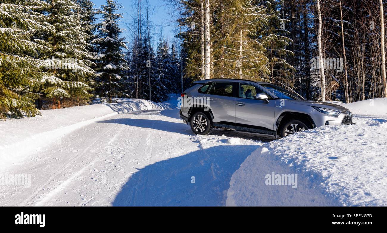 2023 Toyota RAV4-Plug-in parkt an der verschneiten finnischen Forststraße in Winter, Finnland Stockfoto