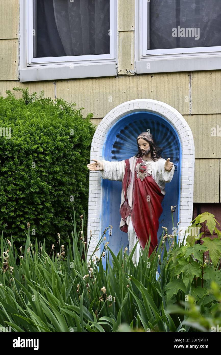 Eine Statue von Jesus Christus in Gewändern in einer blau-weißen Nische im Vorhof eines Hauses in Brooklyn, sichtbar im Hintergrund (gelbe Seite). Stockfoto