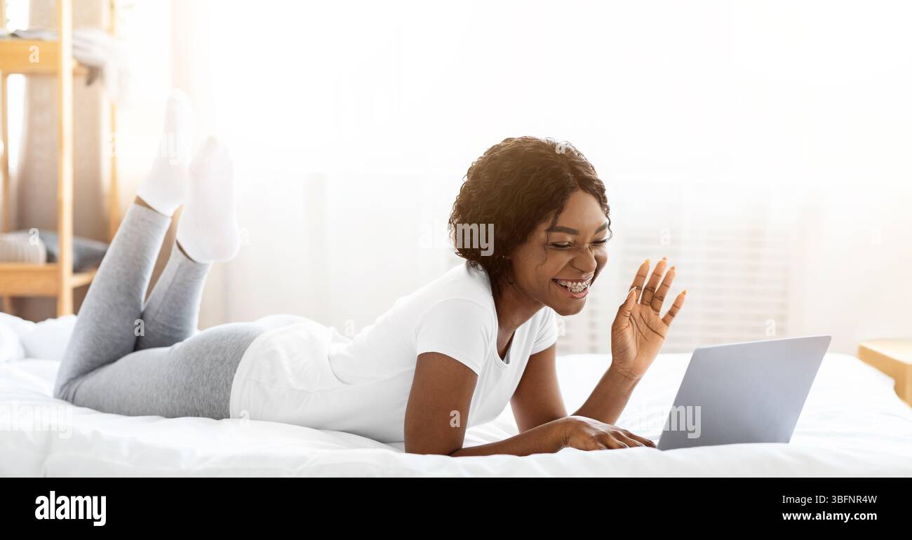 Nette schwarze Dame mit Videoanruf auf Computer von zu Hause Stockfoto