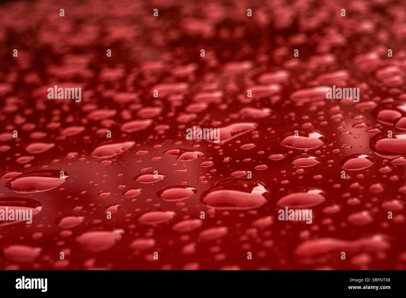 Wassertropfen auf glänzendem rotem Metall Stockfoto