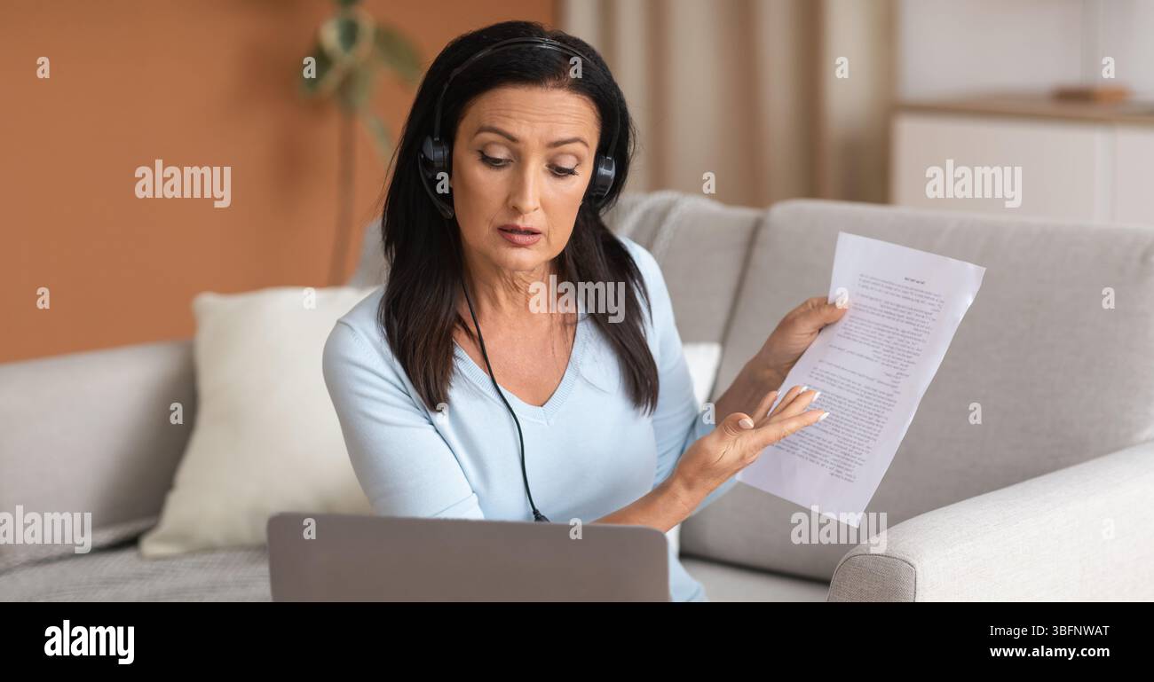Frau im Headset sitzt am Schreibtisch, mit Videoclip am Computer Stockfoto