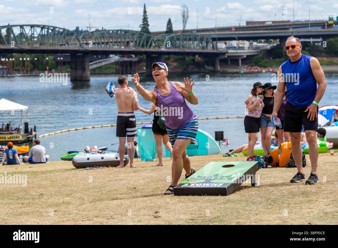The Big Float, Portland, Oregon – 13. Juli 2019: Eine Frau wirft einen Sitzsack während eines Maisloch-Spiels beim Big Float Event am Willamette River. Stockfoto
